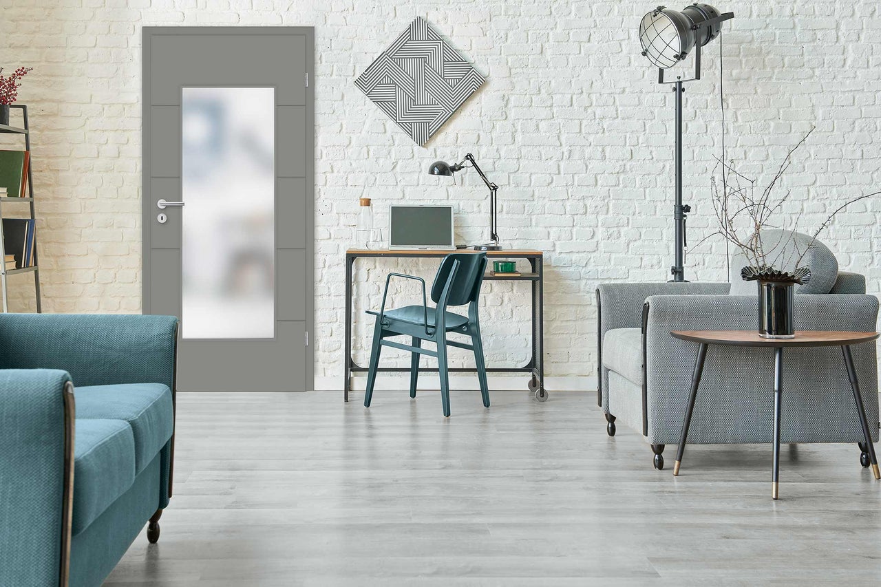 Salon moderne avec porte intérieure grise, canapé, bureau et décoration