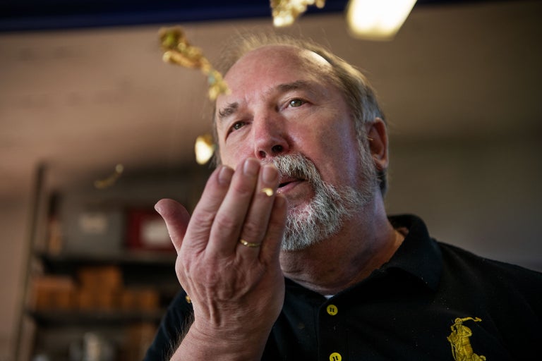 Mann bläst Blattgold von seiner Hand