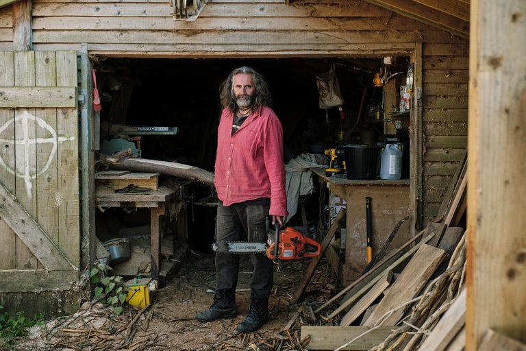 Mann mit Husqvarna Motorsäge vor einer Werkstatt