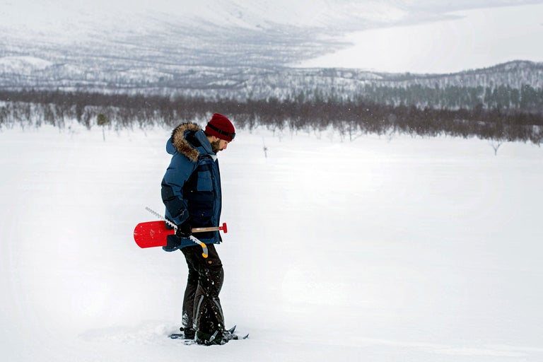 Homme avec pelle pliante rouge dans la neige