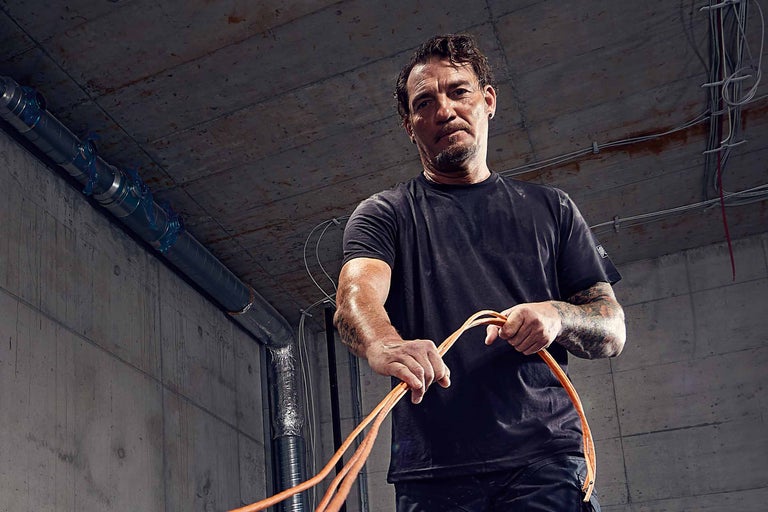 Un électricien tient des câbles électriques dans un bâtiment en construction