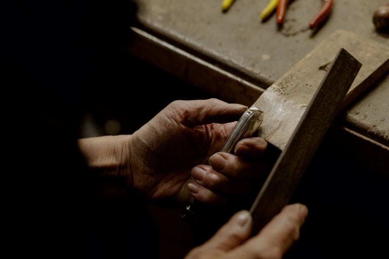 Gros plan des mains travaillant un morceau de métal avec une lime