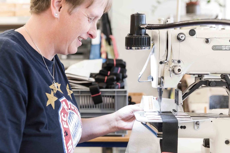 Frau arbeitet mit einer Industrienähmaschine an einem Textilprodukt