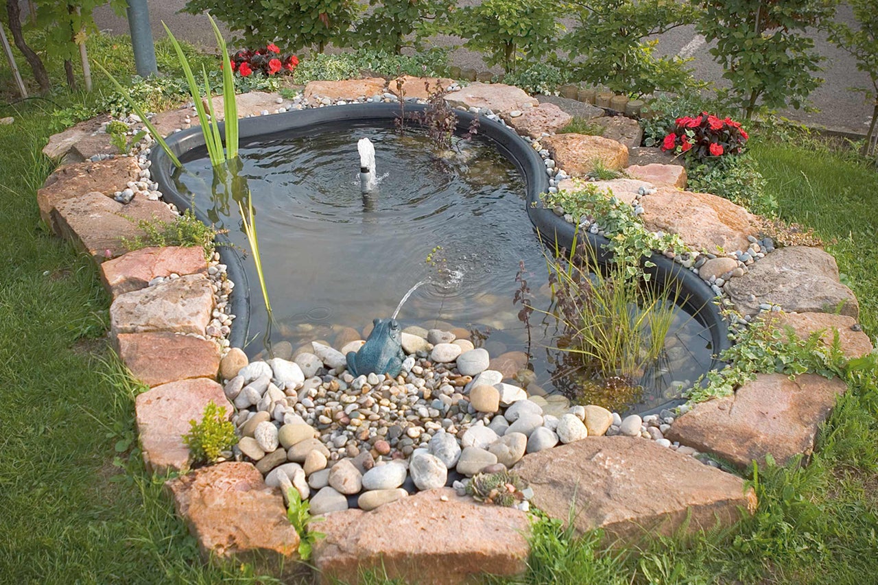 Bassin de jardin avec pierres, plantes et figurine de bassin