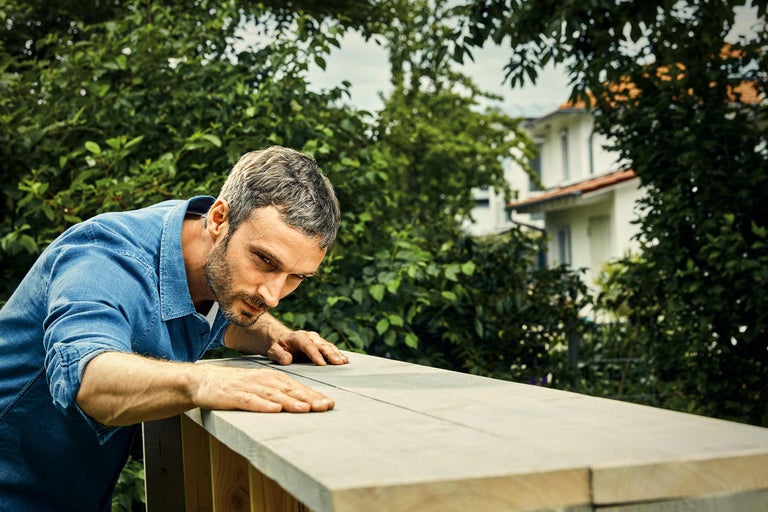 Homme inspectant une construction en bois dans le jardin