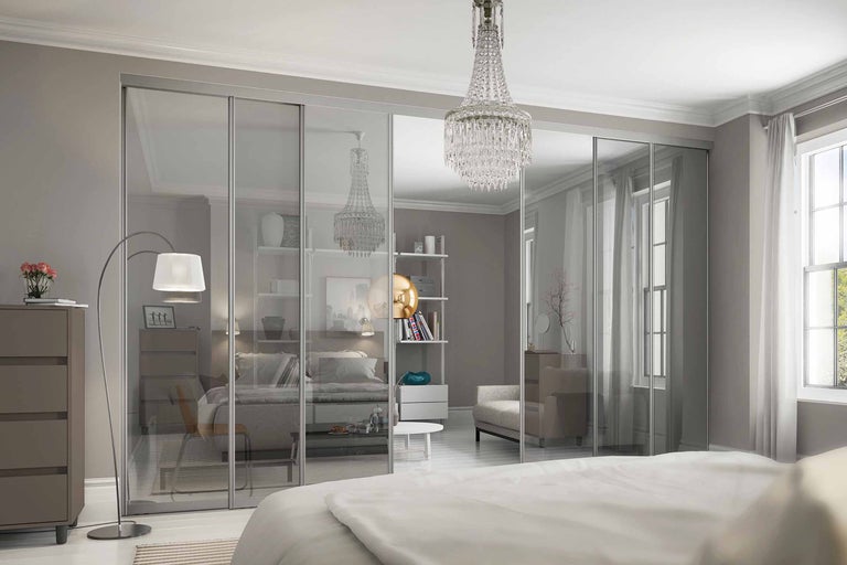 Schlafzimmer mit Glasschiebetüren, Bett und Kristalllüster für ein helles und organisiertes Ambiente.