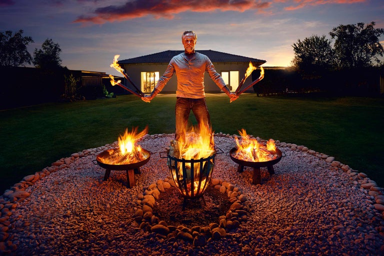 Homme avec des torches et des braseros dans le jardin au crépuscule