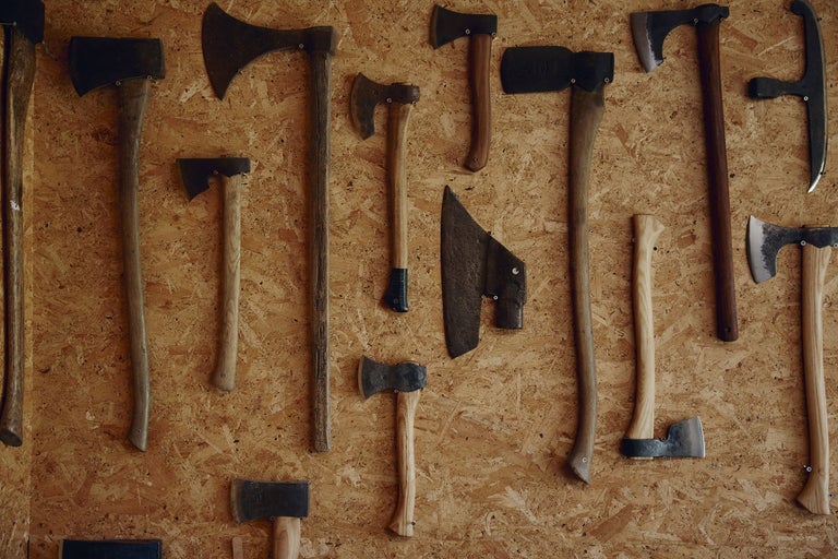 Verschiedene Äxte und Beile an einer Holzwand.