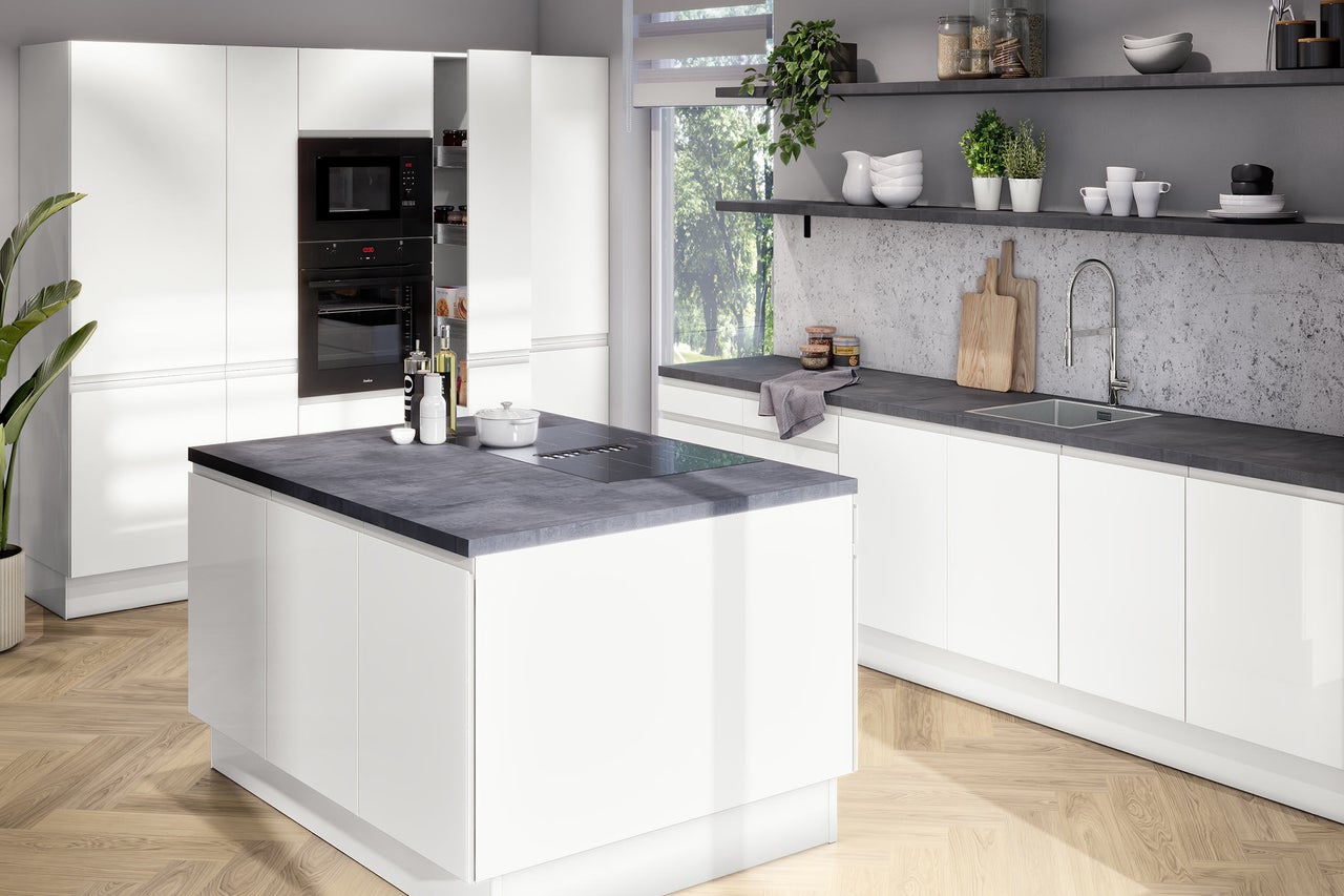Cuisine moderne et lumineuse avec des meubles blancs sans poignées, un îlot central avec plan de travail foncé et parquet en chevrons.