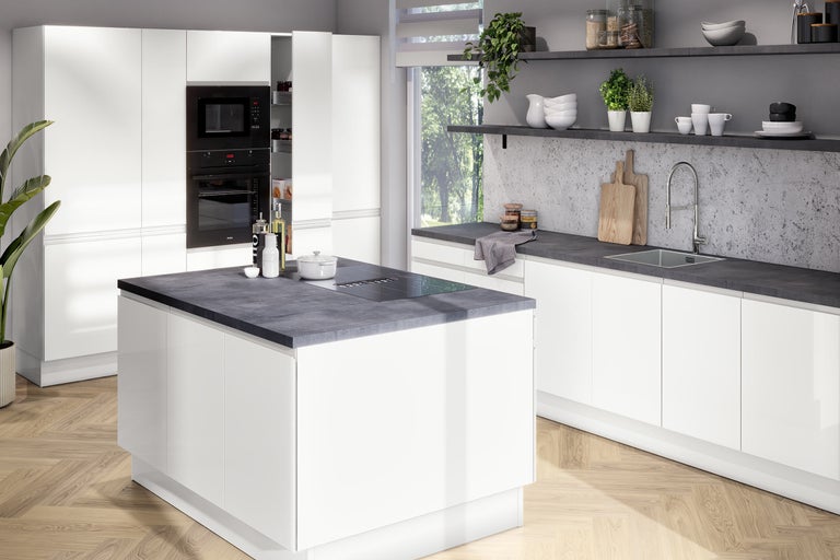 Cuisine moderne et lumineuse avec des meubles blancs sans poignées, un îlot central avec plan de travail foncé et parquet en chevrons.