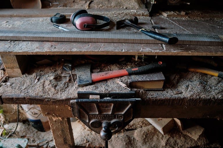 Werkbank mit Werkzeugen wie Hammer, Axt, Schraubstock, Stift, Maßband und Gehörschutz