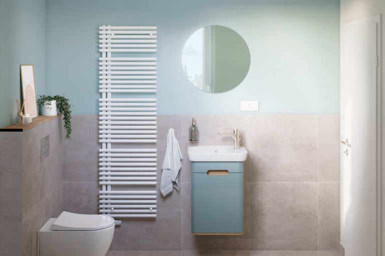 Salle de bains lumineuse avec toilettes, meuble sous-lavabo, radiateur et miroir