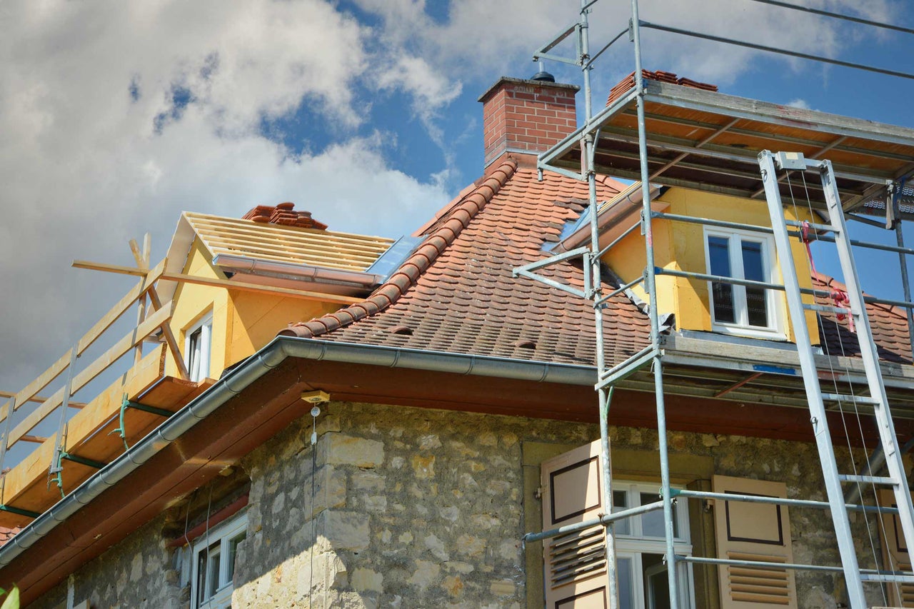 Haus mit Gerüst, Dachziegeln und Dachrinnen für Dacharbeiten