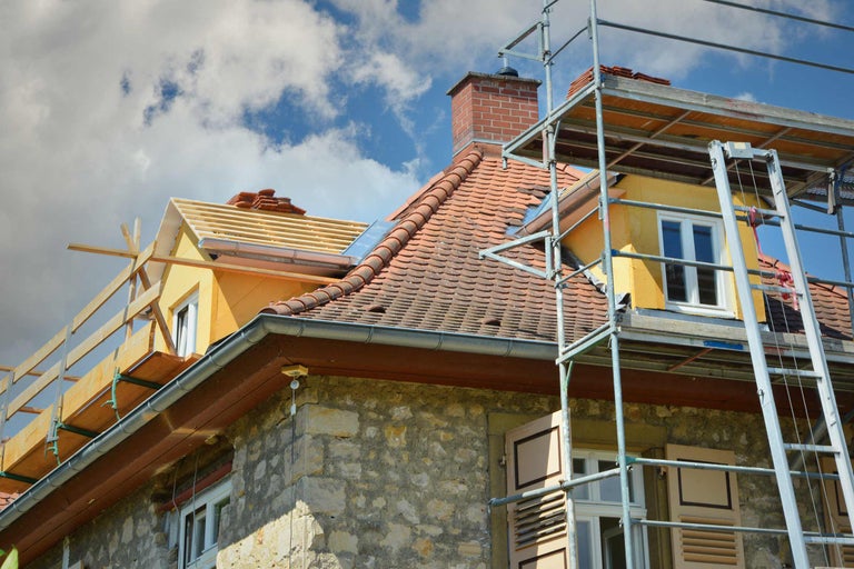 Haus mit Gerüst, Dachziegeln und Dachrinnen für Dacharbeiten