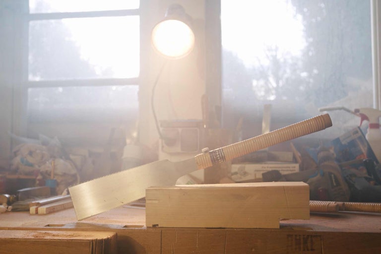 Japanische Zugsäge beim Schneiden eines Holzstücks auf einer Werkbank.