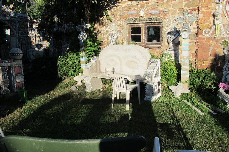 Gartenbereich mit dekorativer Bank, Stuhl und mosaikverzierter Mauer