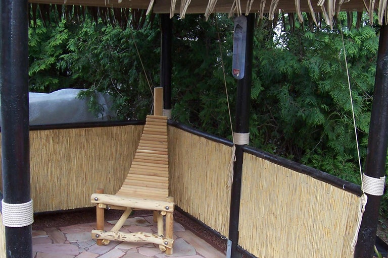 Scène d'une tonnelle de jardin avec une clôture en bambou et une chaise en bois