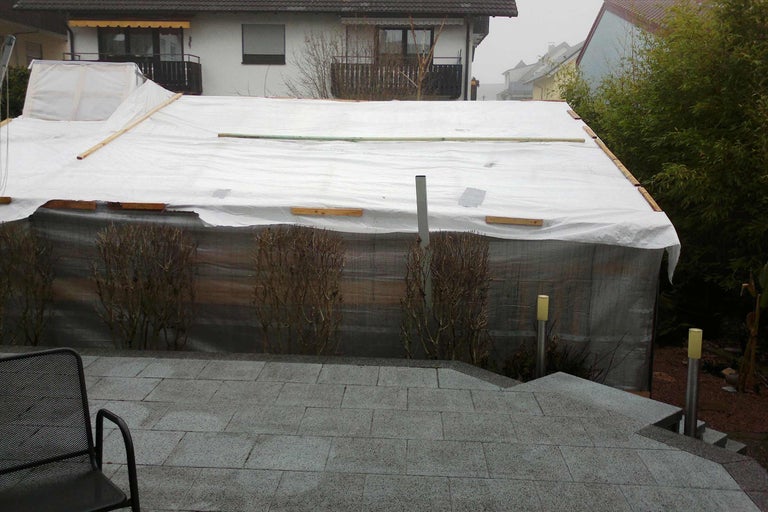 Piscine couverte dans le jardin avec bâche et structure en bois.