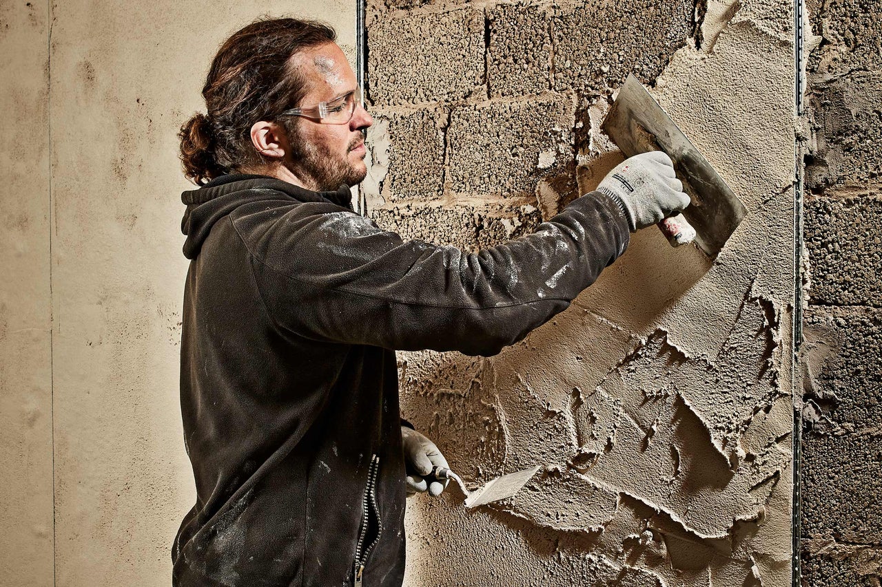 Un artisan applique du plâtre sur un mur avec une truelle