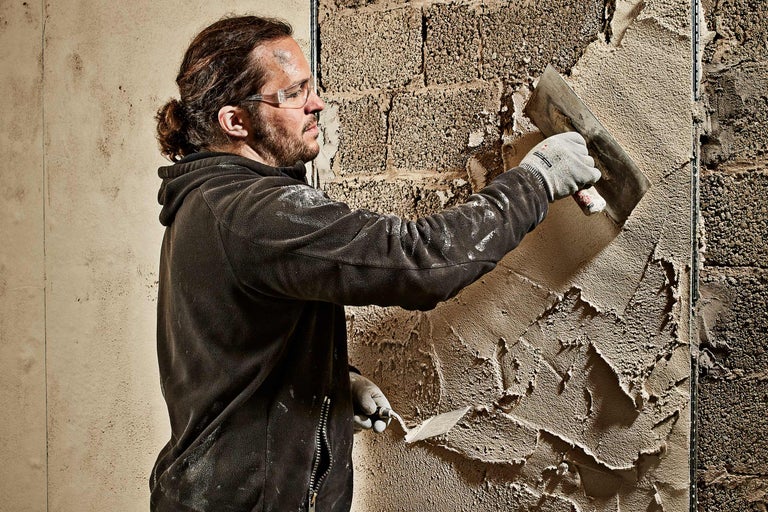 Un artisan applique du plâtre sur un mur avec une truelle
