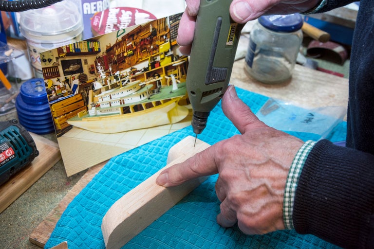 Eine Person bohrt mit einem Bohrer in ein Holzstück, um ein Modell zu erstellen.