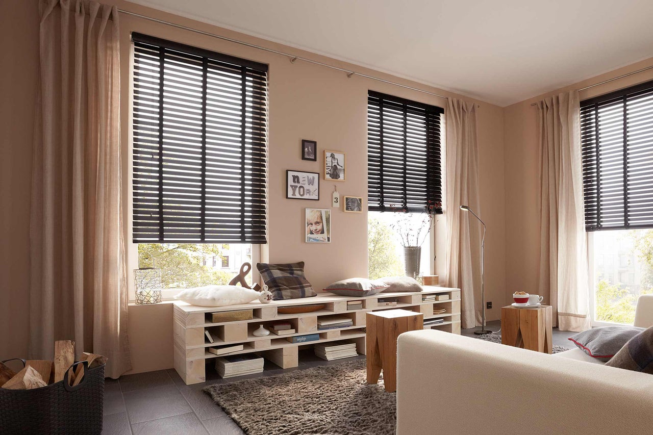 Salon avec fenêtre, stores vénitiens en bois et rideaux pour l'intimité et la décoration