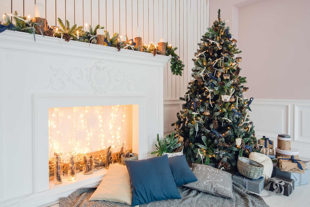 Sapin de Noël décoré à côté d'une cheminée avec décoration et cadeaux