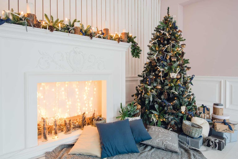 Sapin de Noël décoré à côté d'une cheminée avec décoration et cadeaux
