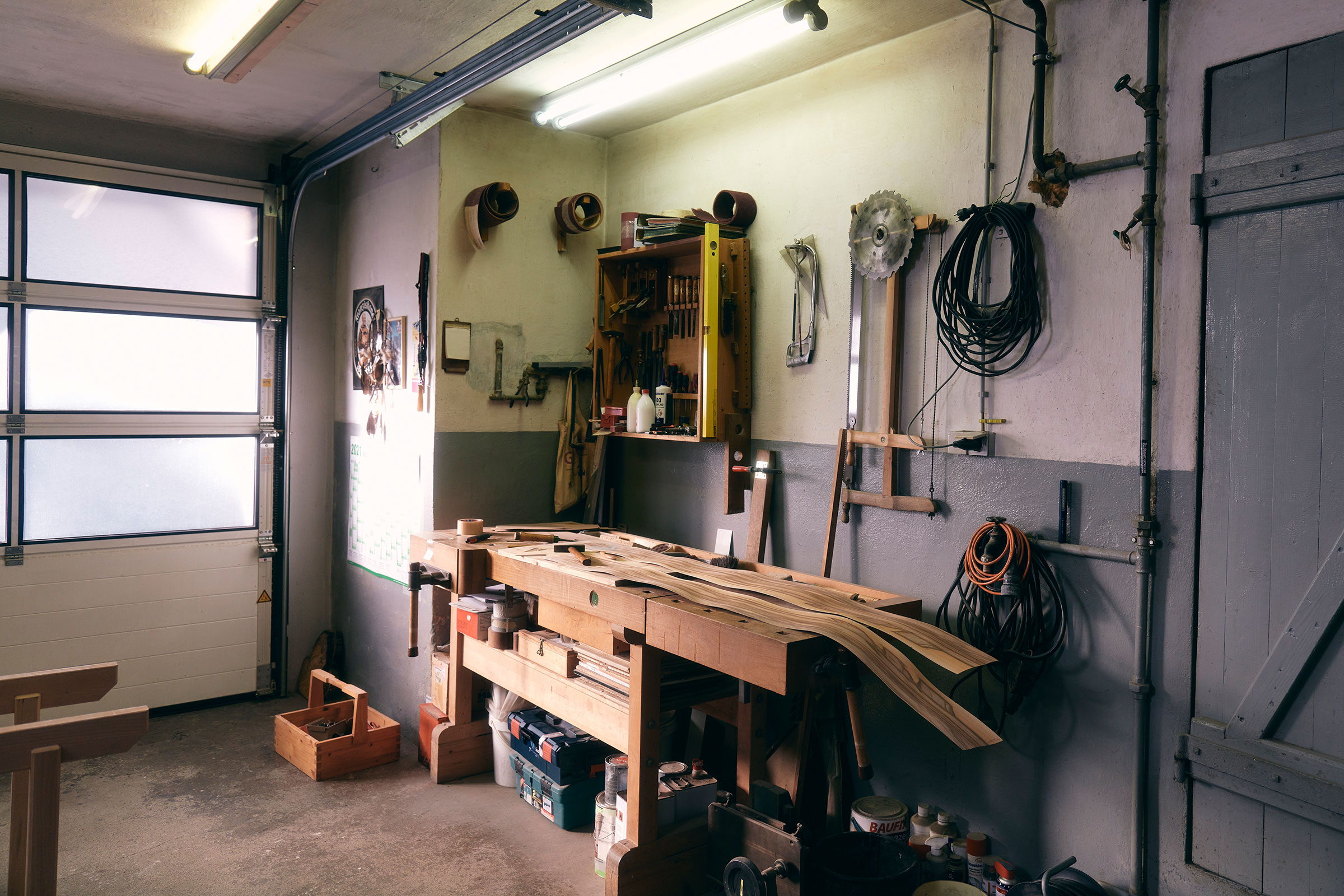 Werkstatt mit Werkbank, Werkzeugen und Holzbalken