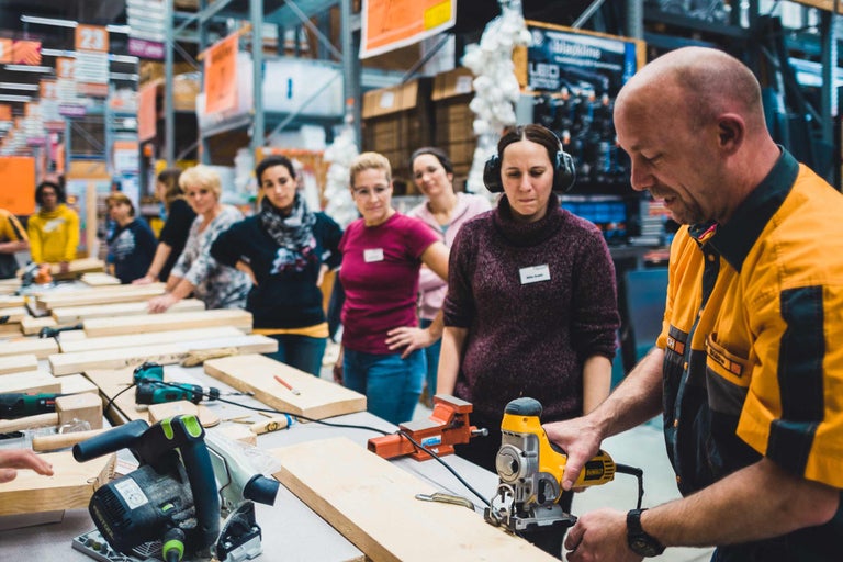 Un groupe de personnes participe à un atelier avec des outils de travail du bois Dewalt.