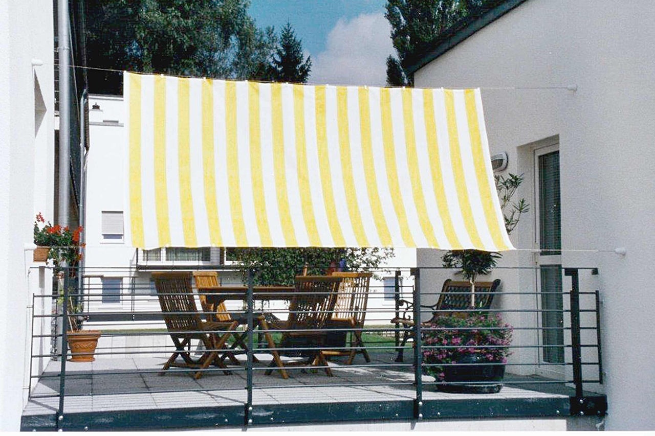 Balcon avec store, table et chaises d'extérieur.