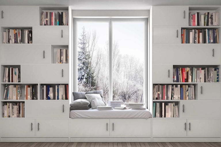Bibliothèque blanche avec coin fenêtre, coussins et livres