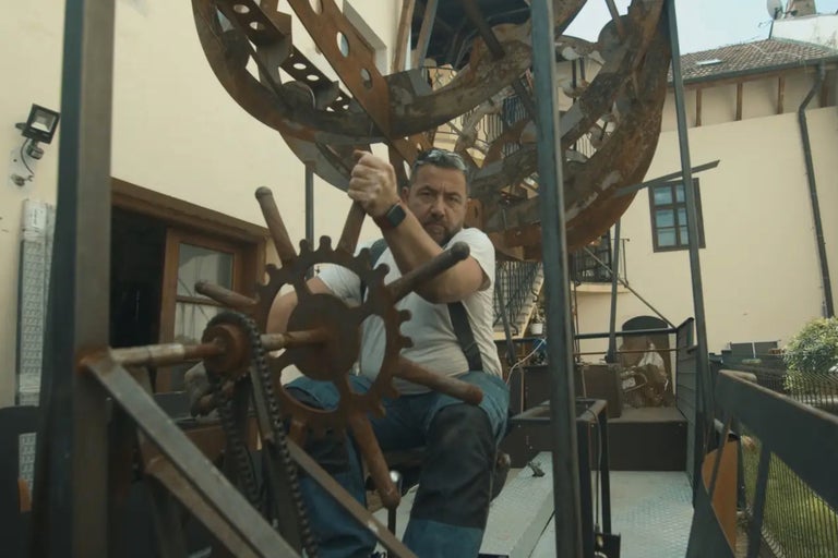 Un homme manipule une grande structure métallique à l'extérieur.