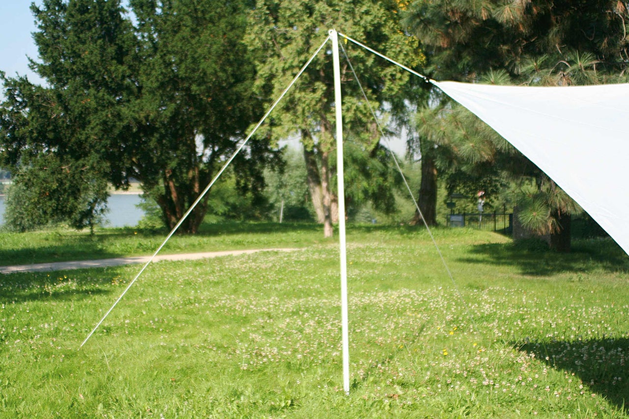 Voile d'ombrage blanche sur une prairie, fixée avec des cordes et une perche
