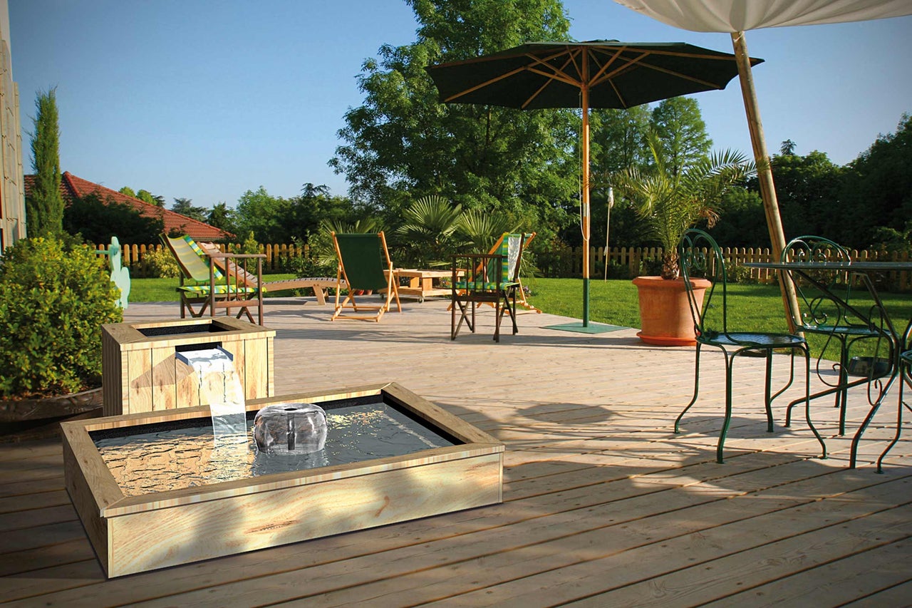 Scène de jardin avec jeux d'eau en bois, mobilier de jardin et parasols sur une terrasse en bois