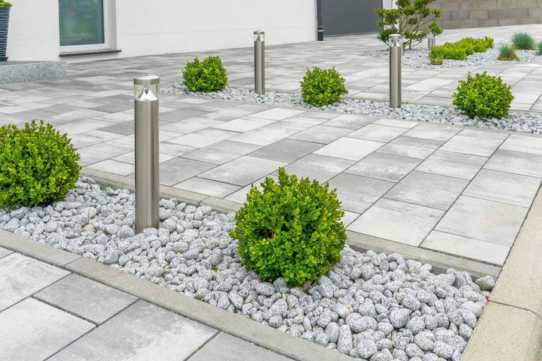 Extérieur avec pavés en béton, gravier décoratif, boules de buis et lampes en acier inoxydable