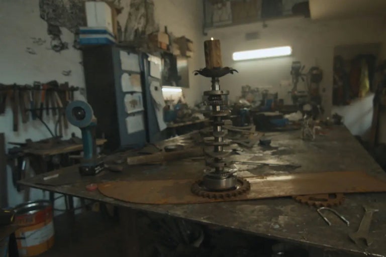 Scène d'atelier avec un chandelier en métal et une bougie allumée sur un établi.