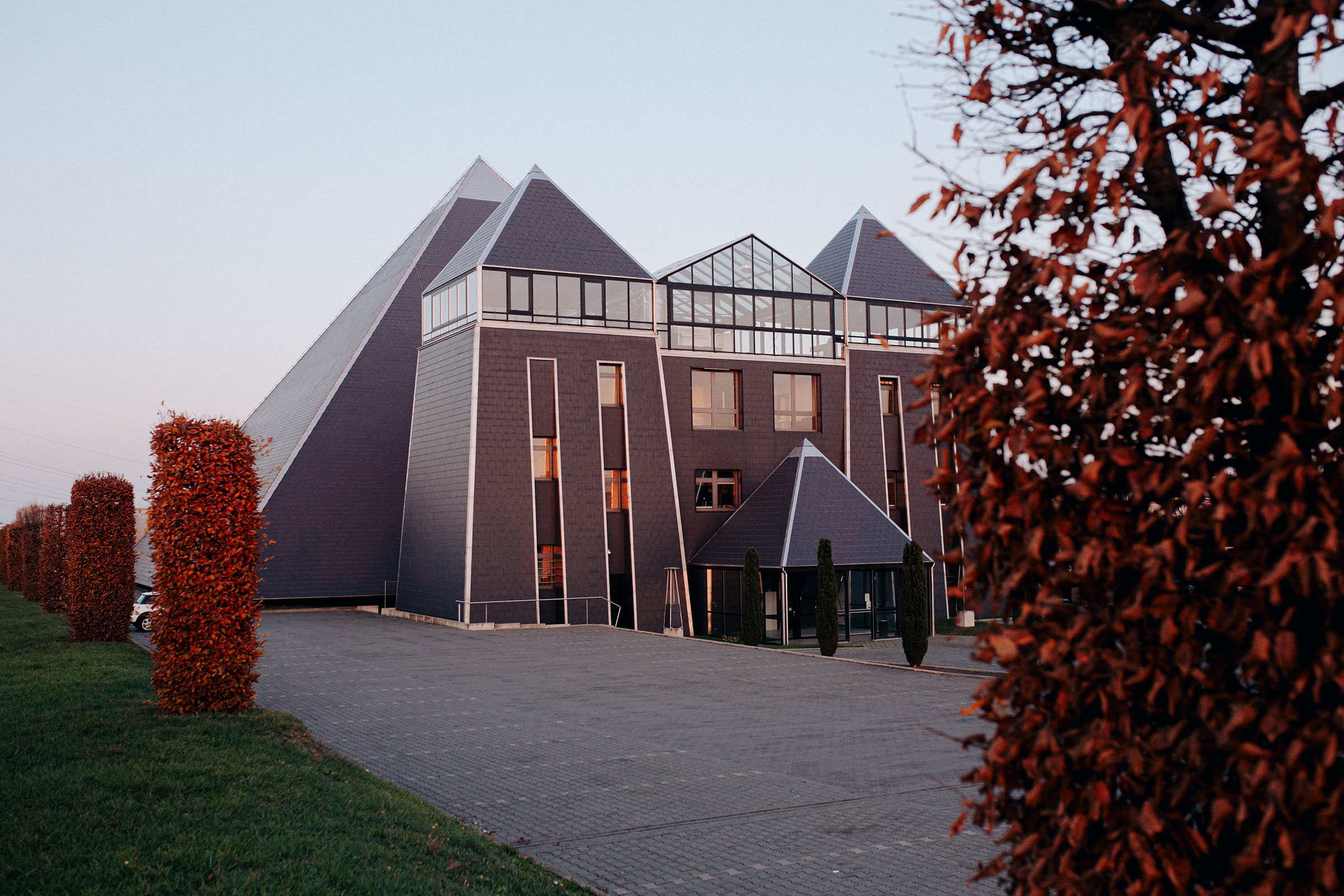 Außenansicht eines Bürogebäudes mit pyramidenförmigen Dächern und angelegten Hecken