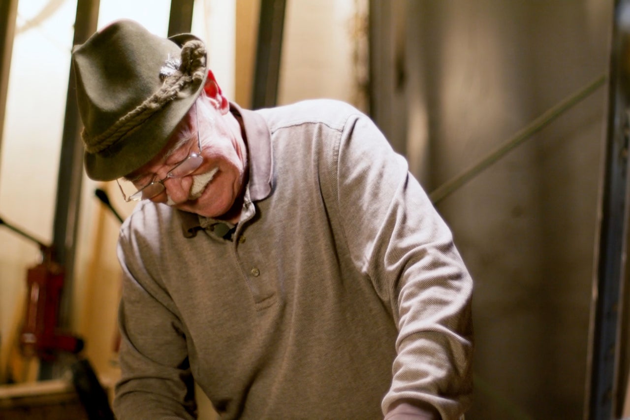 Homme avec un chapeau traditionnel et un polo se penche vers le bas