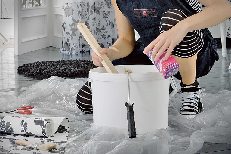 Encapsulage de papier intissé : une personne mélange de la colle dans un seau pour appliquer du papier intissé.