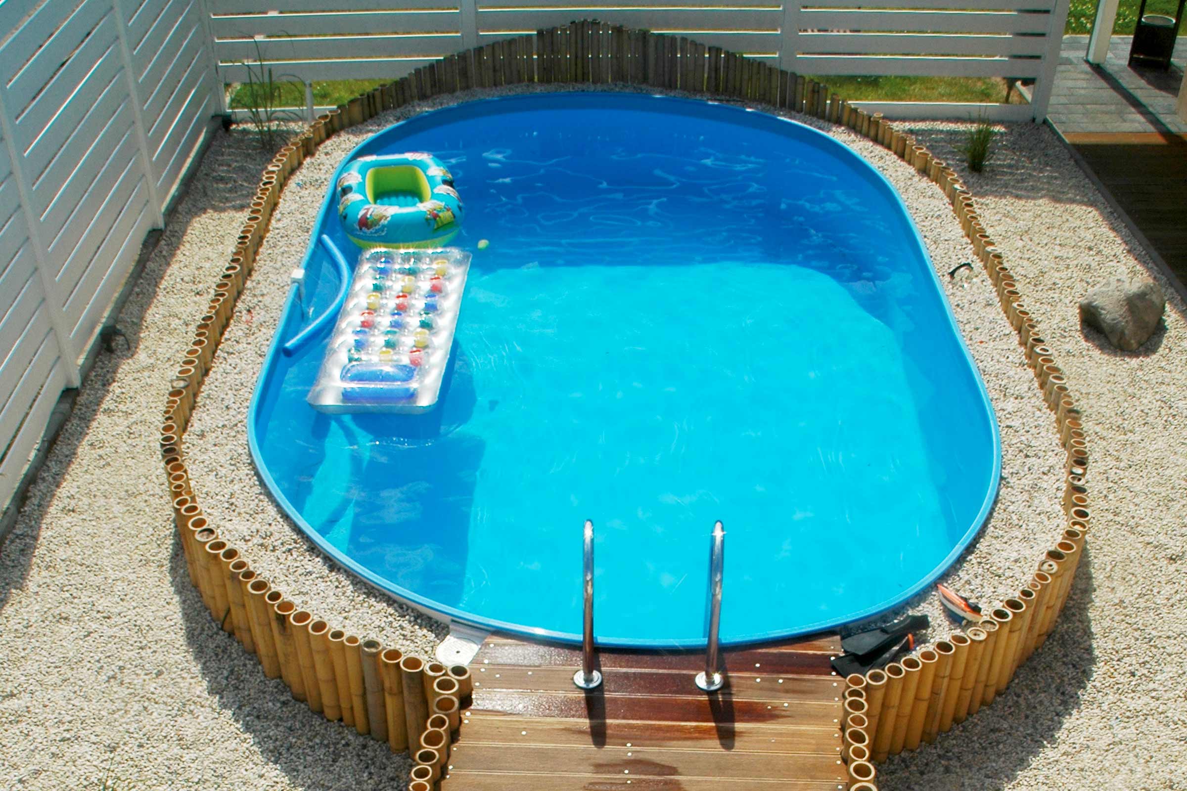 Aufblasbarer Pool mit Leiter und Bambusumrandung im Garten.
