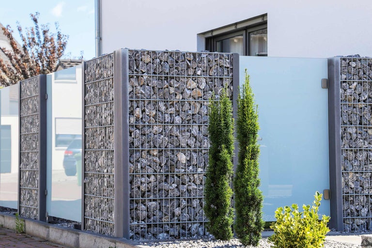 Clôture de gabions avec remplissage en pierre et éléments en verre comme écran d'intimité