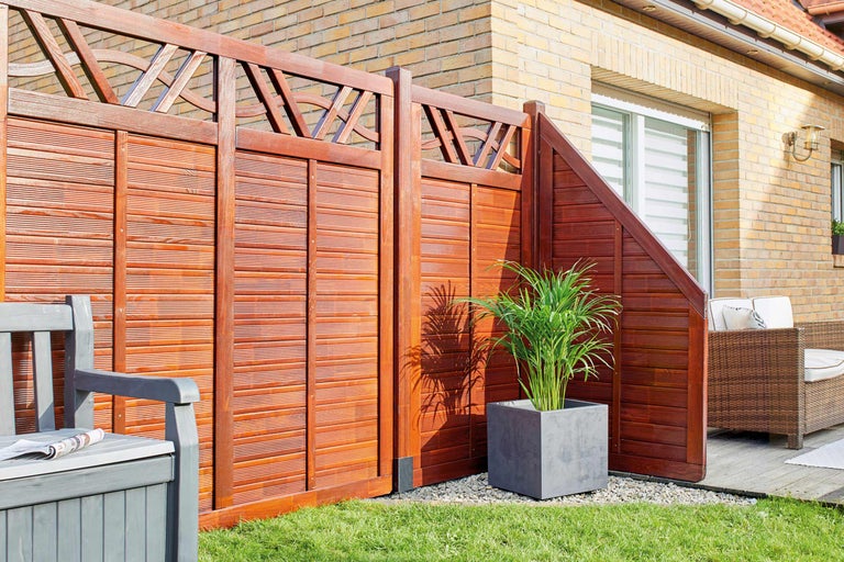 Holzsichtschutzzaun mit dekorativem Element und Sitzbank im Garten