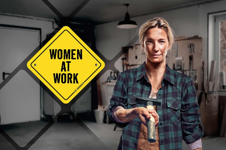 Femme avec un marteau, en arrière-plan un atelier et un panneau portant l'inscription Women at Work de Hornbach
