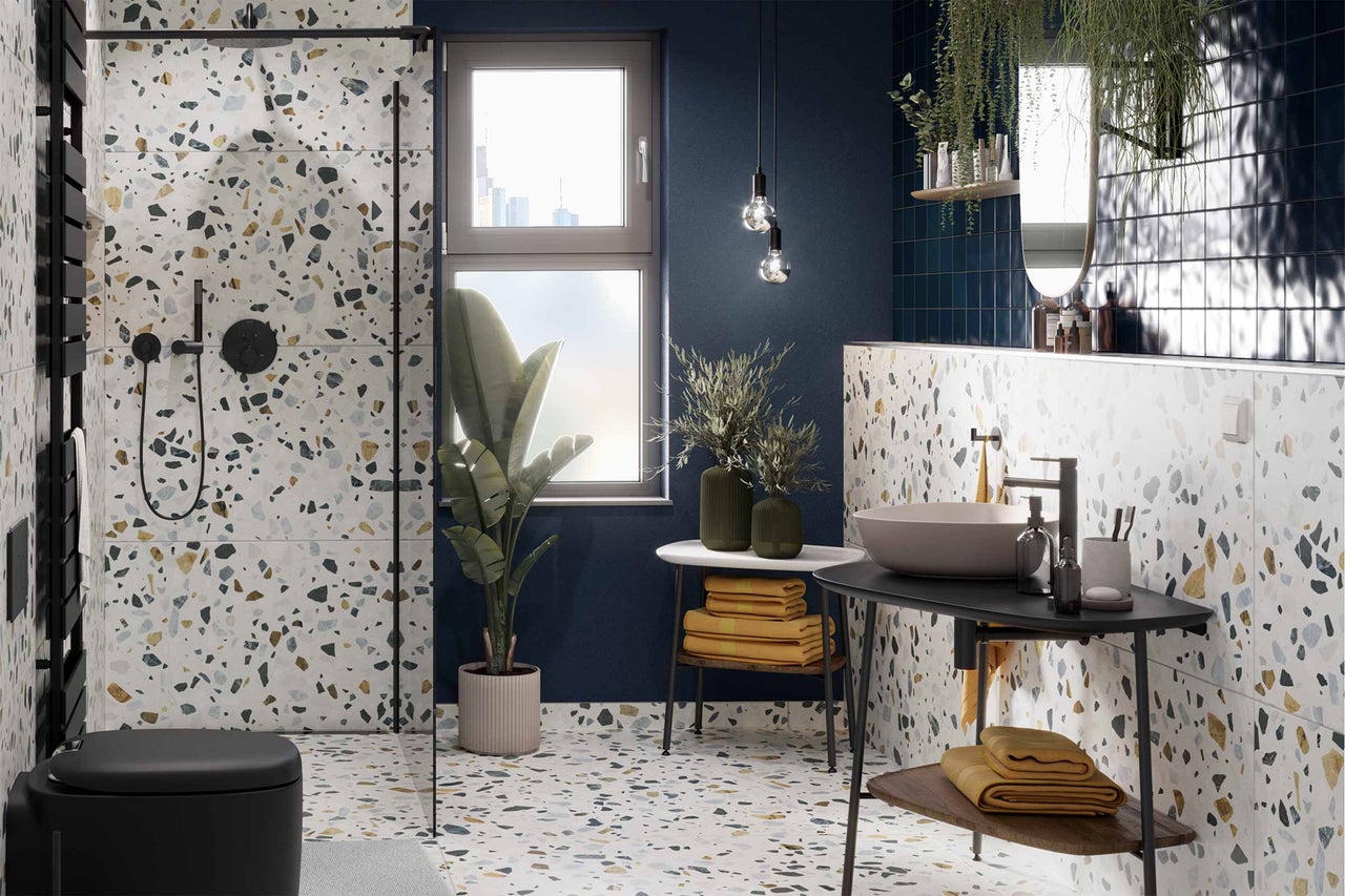Salle de bain moderne avec carrelage terrazzo, douche, lavabo et décorations.