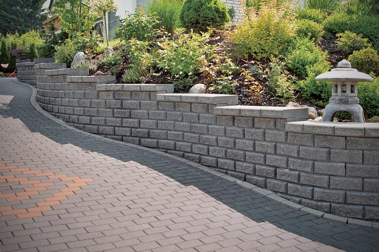 Idée d'aménagement pour un jardin avec mur de soutènement et chemin pavé.