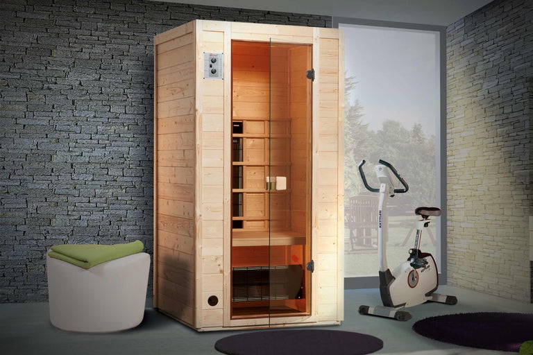 Vue d'intérieur avec sauna en bois, tabouret avec tissu et vélo d'appartement.