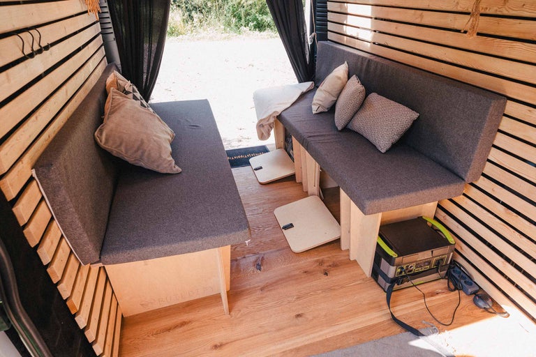 Innenraum eines umgebauten Lieferwagens mit Sitzbereich und Holzwänden