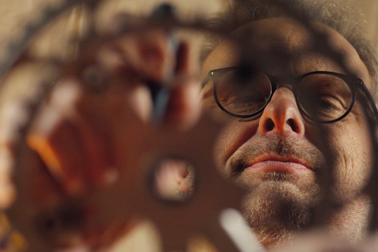Mann mit Brille blickt durch ein Loch