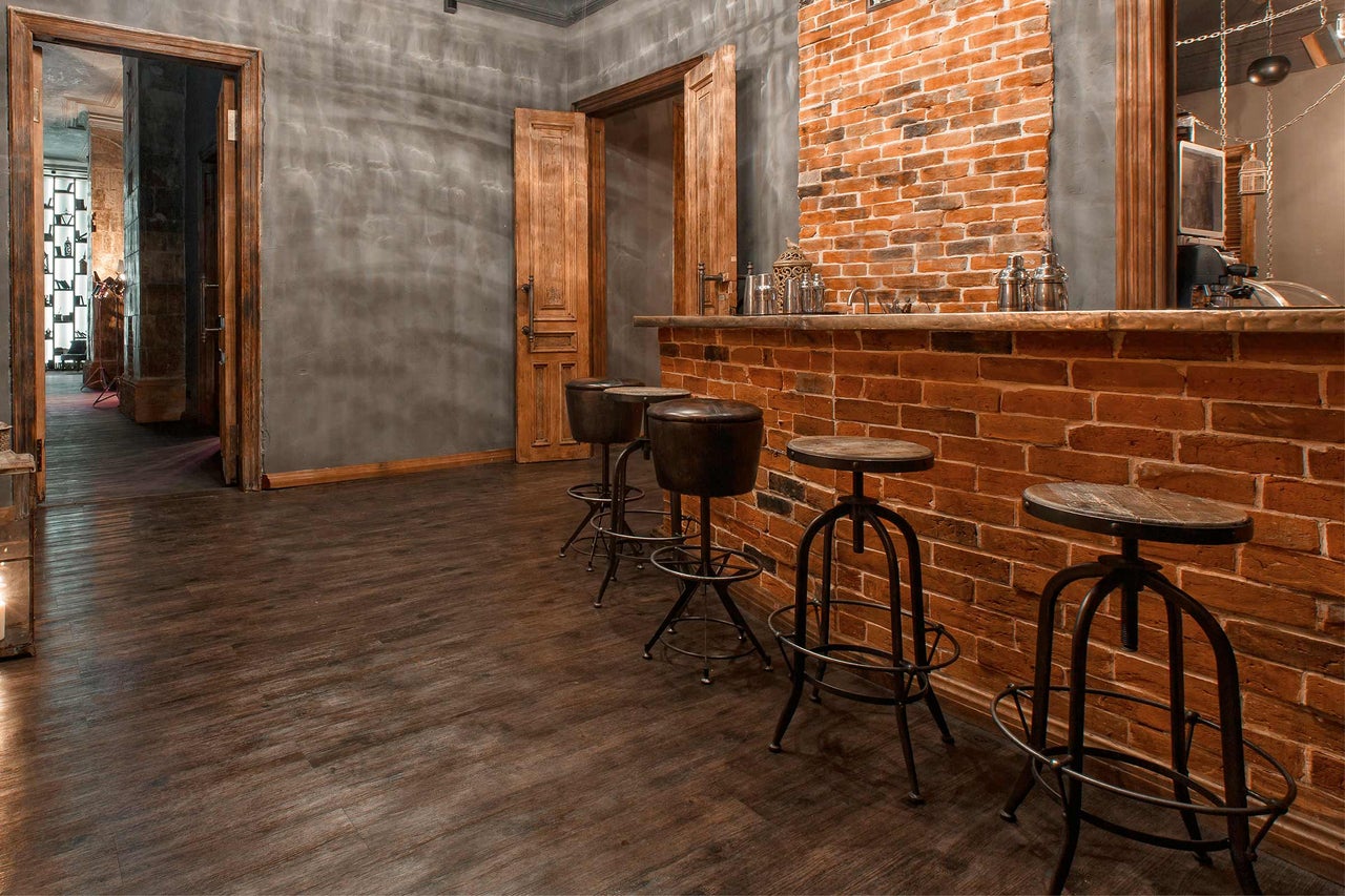 Bar avec comptoir en briques et tabourets de bar dans une pièce avec plancher en bois